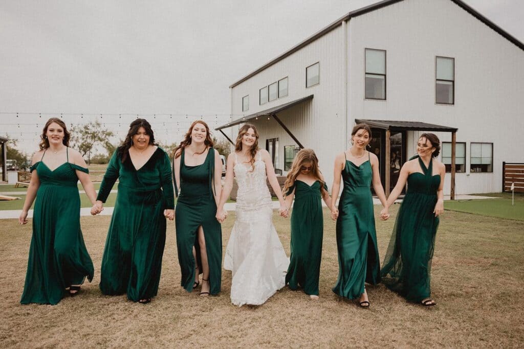 bride walking with bridesmaids in green gowns