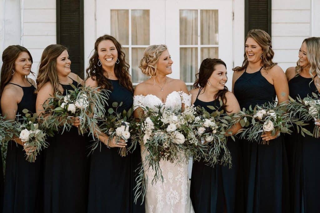 bride with bridesmaids holding large greenery bouquets