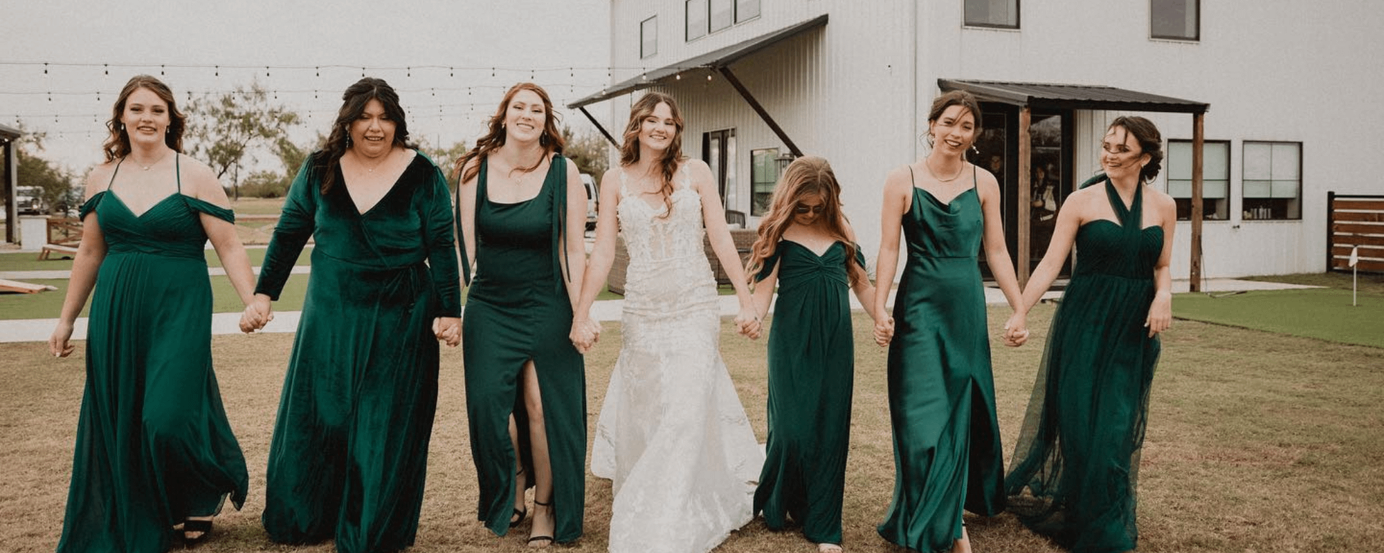 bridal party holding hands standing outside of wedding venue 